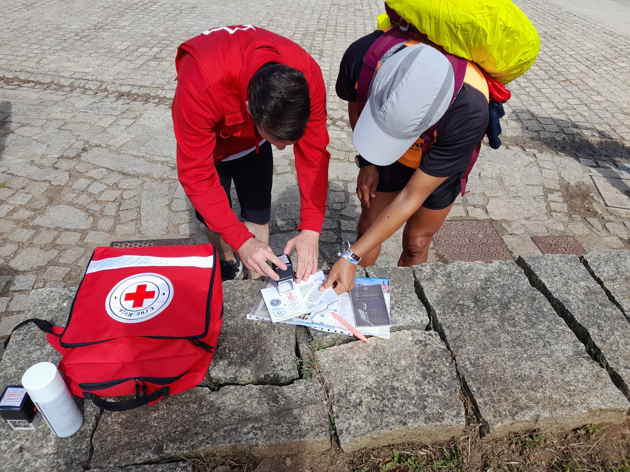 Voluntarios de Cruz Roja sellan la Credencial a un peregrino en el Camino de Santiago